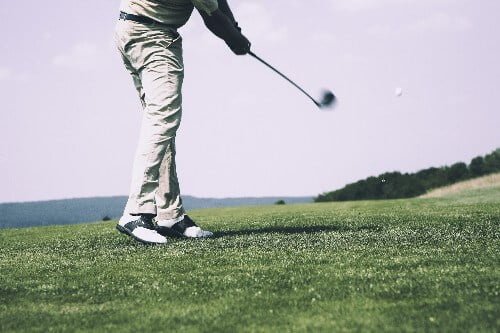 Golfer swinging to show golf shoes are worth it by showing a pivot point